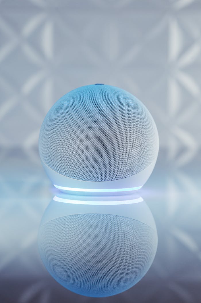 Close-up of an illuminated smart speaker with a reflective surface, showcasing modern technology.