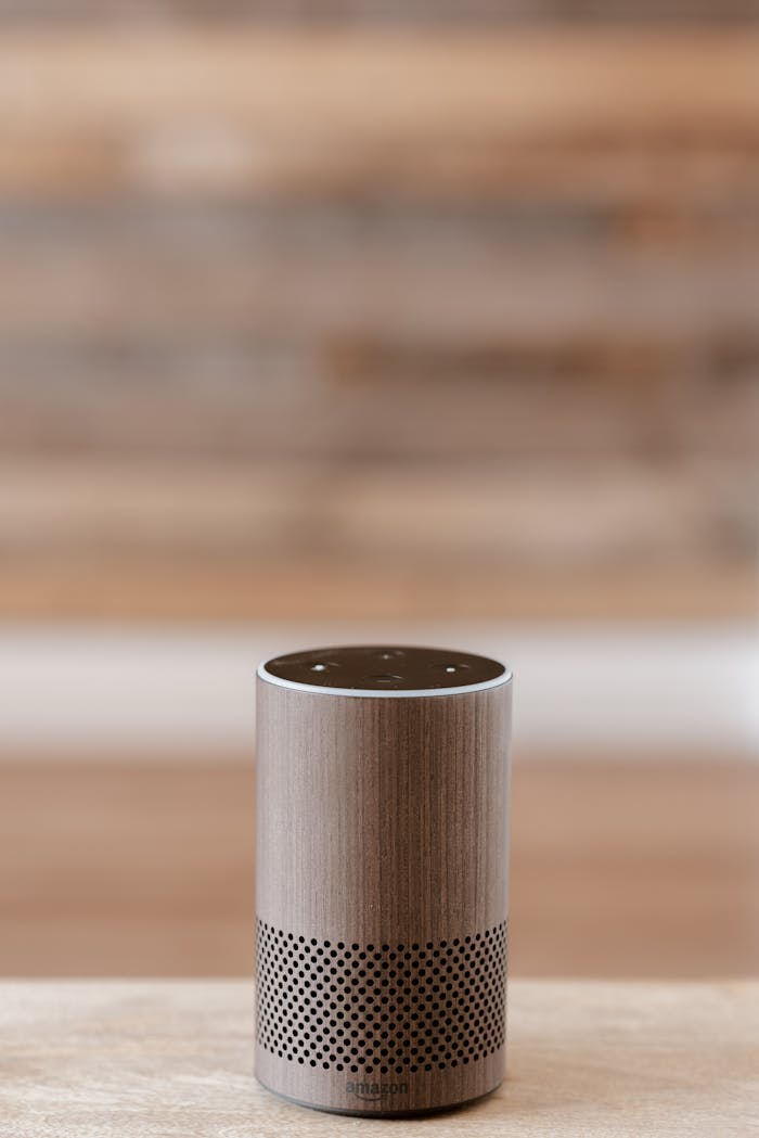 A smart speaker placed on a wooden surface against a blurred background, emphasizing minimalist design.